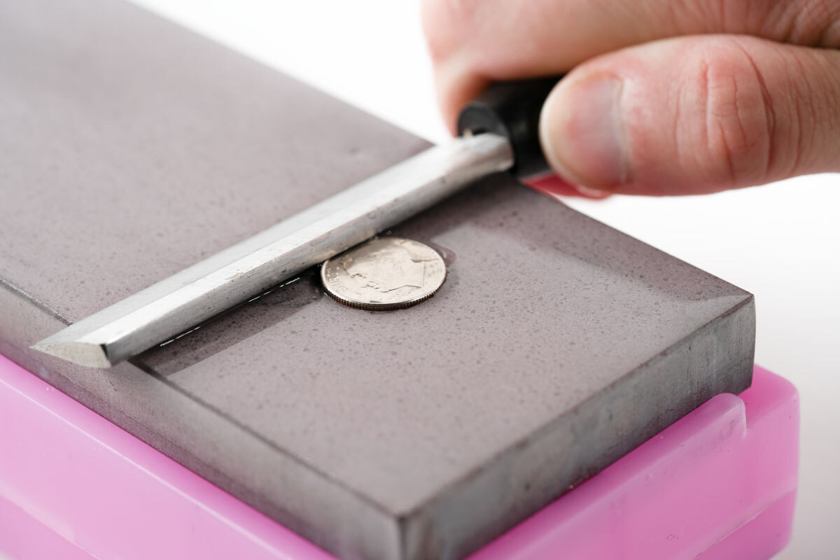 figure 5 Figure 5. Photo of a reed knife liften off the sharpening stone to the height of a dime.